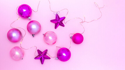 Aerial shot of balls and Christmas stars with small lights on a pink background