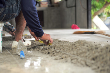 Selective focus on leg and hands of worker mearsuring the floor during installation the floor tiles...