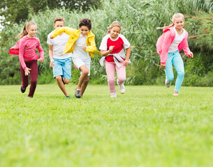 Company of smiling kids are jogning together in the park.