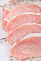 Slices of fresh loin for cooking on rustic board