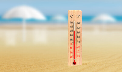Sea coast at hot summer day. Wooden thermometer in the sand. Ambient temperature plus 33 degrees...