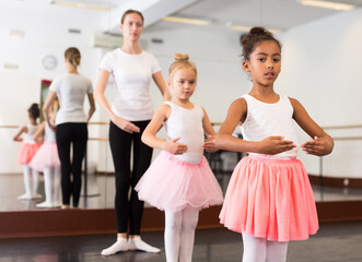 Two little girls practicing choreographic elements in ballet hall