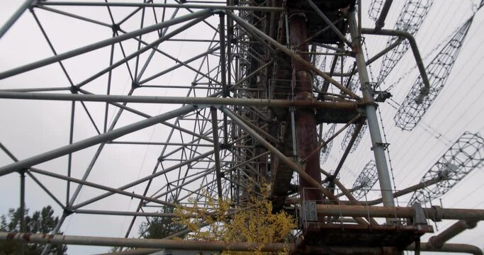Autumnal Trees Under The Rusty Steel Structure Of Duga Antenna At The Duga Radar Station In Chernobyl Exclusion Zone In Pripyat, Ukraine. - tilt up shot