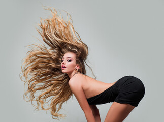Hair in motion. Face of the Beautiful young girl with long straight hair, posing in studio, gray...