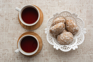 Two cups of tea and wicker basket of gingerbread on background of pastel shades. Tea for two concept