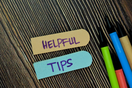 Helpful Tips Write On Sticky Note And Isolated On Wooden Table. Business Concept. Selective Focus On Helpful Tips Text