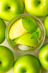 glass with a refreshing drink on the background of green apples.