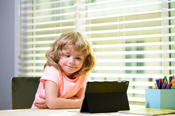 Child home schooling. Online school. Schoolboy doing her homework with digital tablet at home. Child using gadgets to study. Education and distance learning for kids.