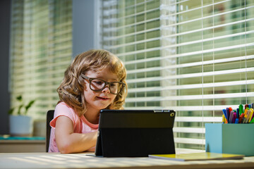 Child in virtual class. School at home. Homeschool little boy student learning in online class with teacher by remote meeting.