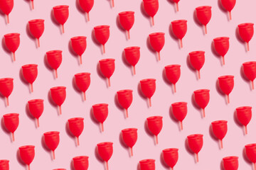 Hot pink menstrual cups on pink background. Reusable female care products. Menstrual cups pattern. Zero waste concept.