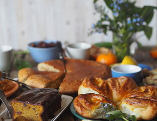 Food background. Home baking buns, cakes and forget-me-not flowers on a wooden table with food.