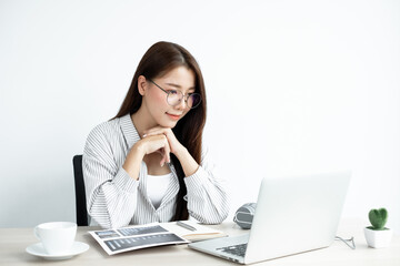 Video call, a young Asian woman wearing glasses communicates via online video long distance, looking at the digital laptop screen, happily greeted with a friend