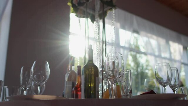 A beautiful room for a party, table setting, glasses and bottles of cognac, wine. Table decoration for the holiday, the sun in the window