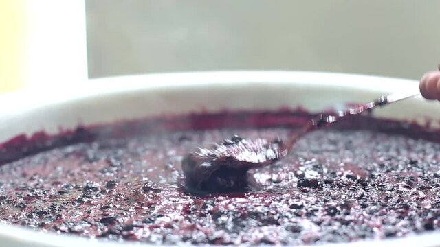 Stir with a spoonful of blueberry jam. Making jam from wild blueberries, jam