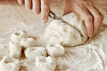 Fototapeta na wymiar woman chef cuts the dough with a knife, female hands in flour, female chef holds the dough, female hands with a knife in flour cut the dough