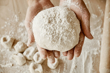 a woman chef is holding the dough, female hands are in flour, a female chef is holding the dough,...