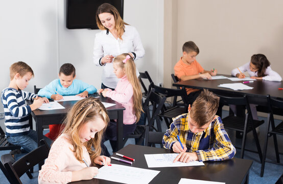 Female teacher and elementary age children drawing at class