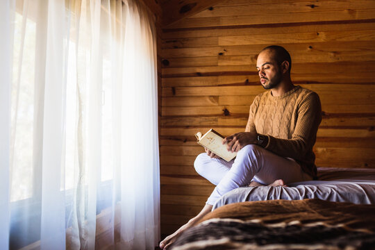 hombre pelón con barba leyendo un libro con un suéter para el frio