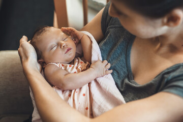 Upper view photo of a caucasian mother with freckles holding her newborn baby covered with a quilt