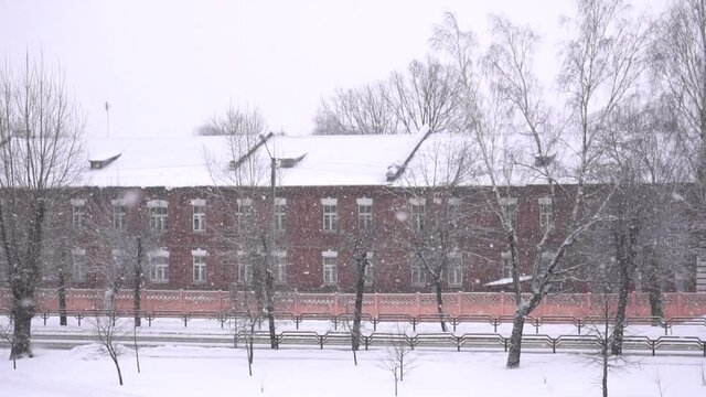 A big snowfall is falling in the city against the background of an old building. Winter, copy space, slow mo