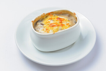Roasted vegetables, potatoes, mushrooms and cheese in a pot. Baked dinner in a white pot. Delicious meal for dinner.