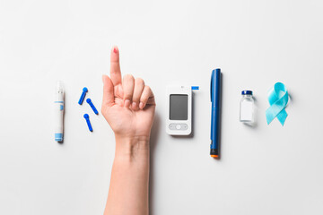 Female hand with awareness ribbon, glucometer, lancet pen, insulin and syringe on white background....