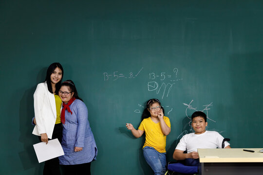 Teacher With Asian Girls With Down's Syndrome And Disabled Boy.