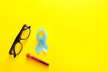 Blue ribbon, eyeglasses and blood sample on color background. Prostate cancer awareness concept