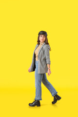 Fototapeta premium Stylish young woman in autumn clothes on color background