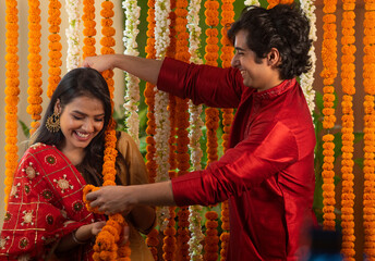 young couple having fun with each other while decorating with flower garlands	