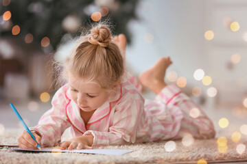 Cute little girl writing letter to Santa at home