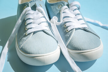 Blue sneakers with white laces on a light blue background. Trendy fashionable casual concept.