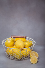 Fresh lemons in a basket on wooden background. Rich source of natural vitamin C.