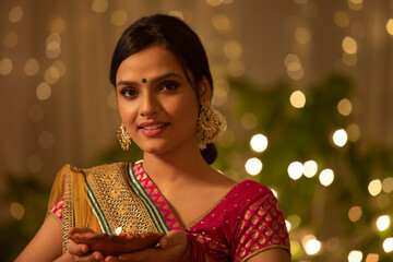 young woman holding a Diwali diya 	