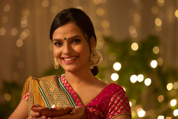 Young woman holding a Diwali diya 	