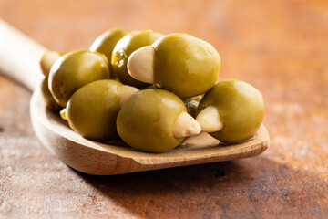 Pitted green olives stuffed with almonds on wooden spoon