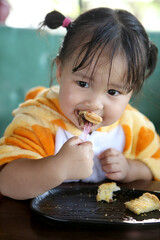 Asian cute girl eating the bread and wearing baby giraffe costume