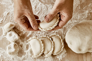 the cook holds dumplings, baker's hands, dough, hands in flour, dumplings, handmade dumplings, ravioli