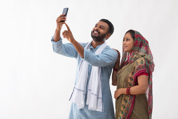 PORTRAIT OF A RURAL HUSBAND AND WIFE CLICKING SELFIE IN MOBILE 
