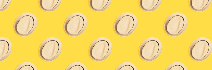 Pattern made of straw hats on a yellow background. Summer concept.