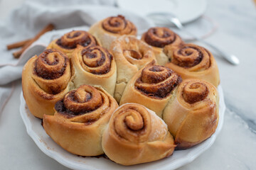 Obraz na płótnie Canvas Cinnamon rolls with sugar frosting. With cinnamon sticks and spices, wooden background