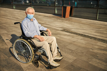 Disabled pensioner in mask looking at the camera