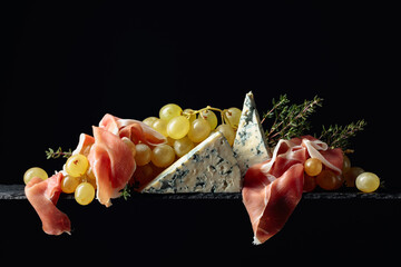 Mediterranean snacks. Grapes with blue cheese, prosciutto and thyme.