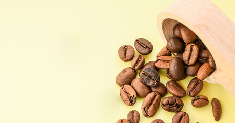 Coffee beans in a wooden spoon isolated on a light background. Сoffee beans are scattered. Place for text.