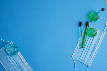 Flat lay. Photo of chemistry glassware putting together on blue working desk with face mask. Covid research