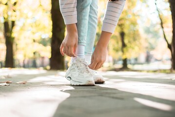 girl in park tying shoelaces
