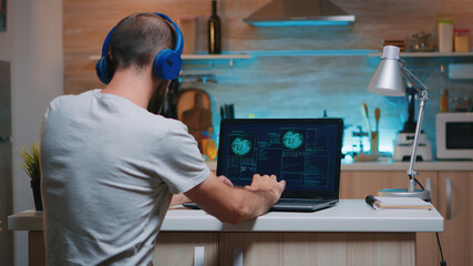 Back view of hacker with headset attacking succesfully the government using finetech, working from home in midnight. Programmer writing a dangerous malware for cyber attacks using performance device