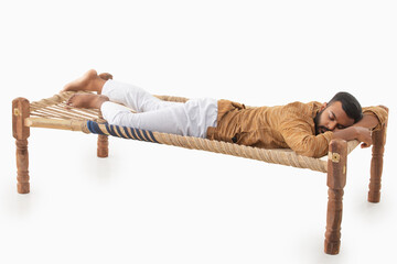 PORTRAIT OF A RURAL MAN SLEEPING ON A COIR COT
