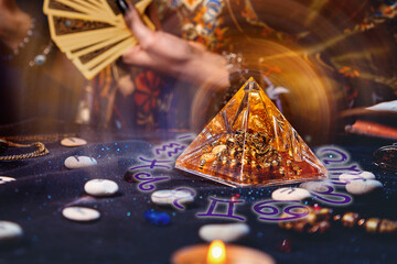 Magic divination and esotericism. Magic glass pyramid with a magical glow. In the background, a...