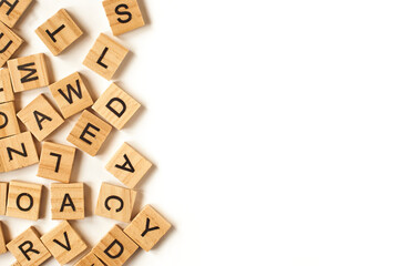Top view of square wooden tiles with the English alphabet scattered on a white background with space for text. The concept of thinking development, grammar.